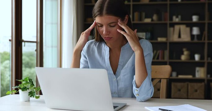 Discontented woman swears at broken or slow computer seated at desk look at device screen feels annoyed, need laptop repair, experiencing lack of understanding, new software, malware, failure concept