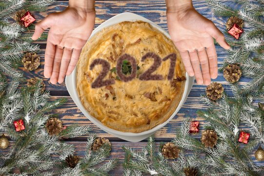 Homemade tart with the number 2021 on cream. Wooden table decorated with pine branches for Christmas and new year