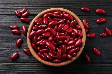 Raw red kidney beans and bowl on dark wooden table, flat lay - obrazy, fototapety, plakaty