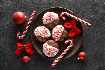Plate with tasty candy cane cookies on black background