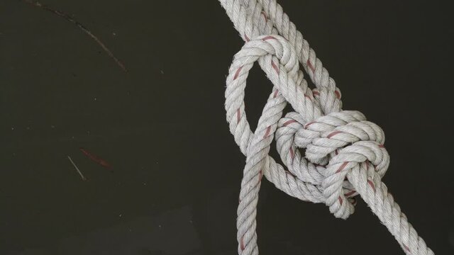 A Close Up Dolly Shot Of A Truckers Hitch Knot, The Rope Securing A Riverboat To The Bank Of The Khwae Noi River In Kanchanaburi, Thailand