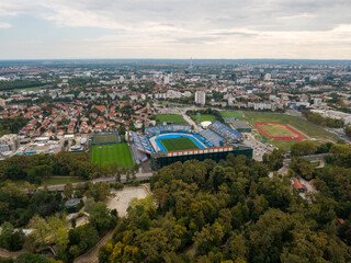 Drone shot of a beautiful city with red roof buildings and a green stadium  in Zagreb, Croatia