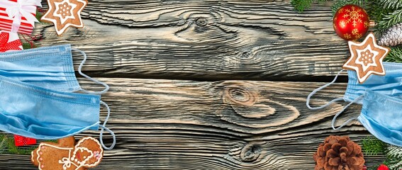 Christmas during COVID 19 pandemic concept with decorations, face masks over wood background.