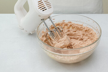 The chocolate cake frosting recipe. Mix of butter, vanilla, and cocoa powder in a glass bowl close up