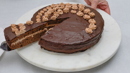 Slice of chocolate cake with chocolate cream topped with chocolate ganache