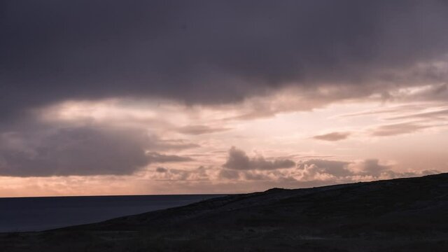 Pink and violet sunset above the sea. God-rays piercing through the thick clouds. A ferry passing on the horizon