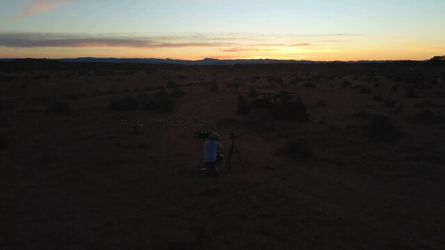 Aerial orbiting person taking pictures of Hawker old car ruins at sunset light outback