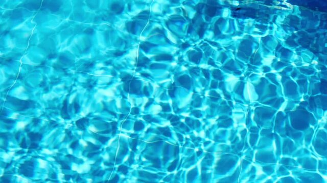 Topview over the surface of the swimming pool. Water shining in swimming pool on sunny day. Slow motion