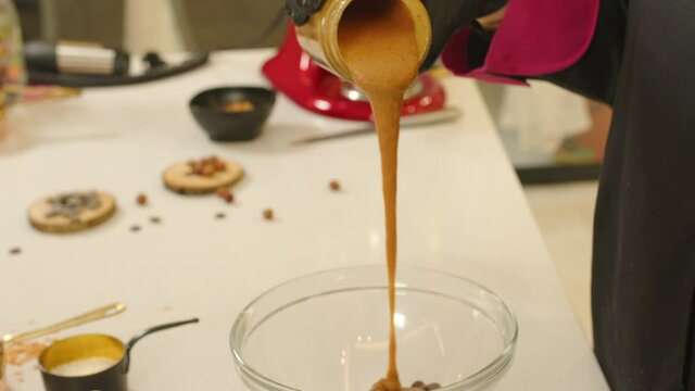Close up of hands pouring praline dough into bowl. Gimbal, shallow focus