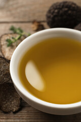 Fresh truffle oil in bowl on table, closeup