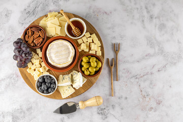 Top view of tasty charcuterie board with cheese, grape, nuts, olives, and ham on a circle kitchen plate