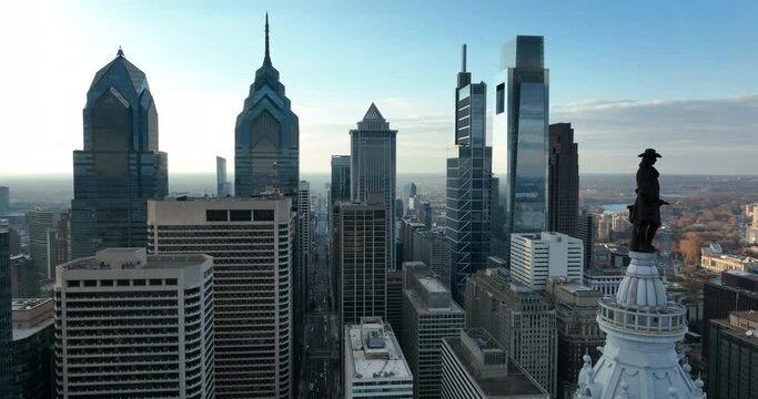 Aerial pullback reveals Philly skyline. Phila PA is large city in Pennsylvania USA. William Penn statue overlooks view.