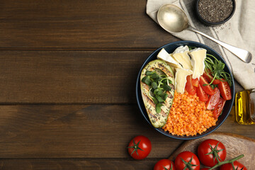 Delicious lentil bowl with soft cheese, avocado and tomatoes on wooden table, flat lay. Space for text