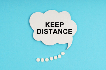 On a blue table are pills and a white plate with the inscription - KEEP DISTANCE