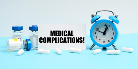 An alarm clock, pills, injections and a card with the inscription - Medical Complications