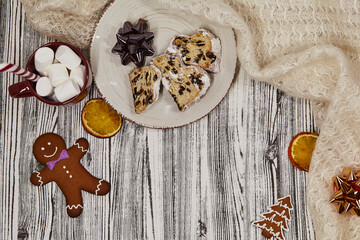 Christmas food and decoration: stollen, chocolate, gingerbread,hot beverage with caramel candy stick. Gift, festive bow and tangerines Christmas background. Copy space