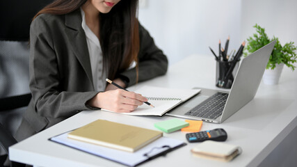 Businesswoman working at her office desk, writing on her personal book.