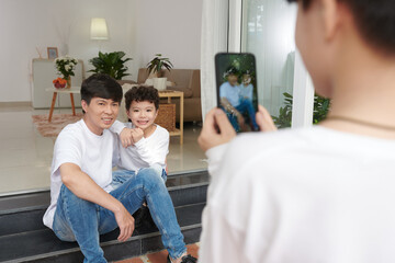 Smiling father and son posing for photo on smartphone at home © DragonImages
