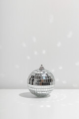 Fototapeta na wymiar Silver disco ball reflects sunlight on silver background.