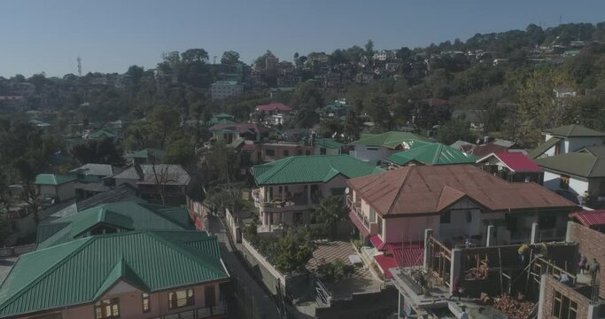 Flying over some residential buildings on the foothills of the Himalayas in India. A Himachali town is seen under development and infrastructure growth since the tourism industry boomed.