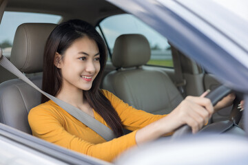 Obraz na płótnie Canvas Young beautiful asian women getting new car. she very happy and excited. she sit and touching every detail of car. Smiling female driving vehicle on the road