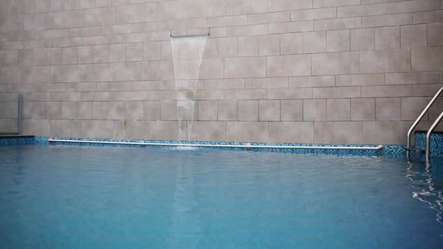 Pan left shot of swimming pool with waterfall