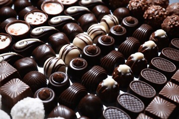 Many different delicious chocolate candies as background, closeup view