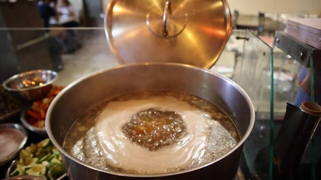 Boiling water in a casserole making soup with spices and herbs. Close up view