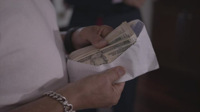 A man pulls out cash from an envelope and counts the money