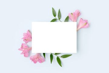 Floral frame made of alstroemeria flower on a blue background. Paper card mockup. Holidays concept...