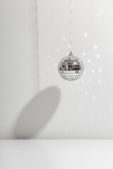 Silver disco ball reflects sunlight on silver background with shadow. Copyspace.