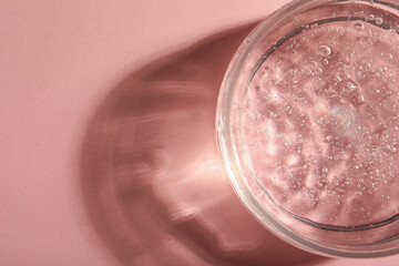 Jar of cosmetic gel on pink background, top view. Space for text