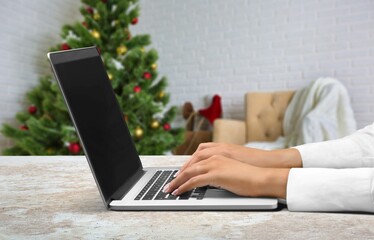 Naklejka premium Young woman work on laptop computer with blank display screen with living room interior design decorated for Christmas,