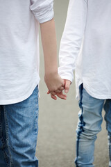 Cropped image of two brothers holding hands when walking in the street