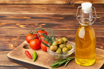 Olive oil, olives and tomatoes on wooden background