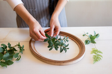 Woman puts branches of plants into frame for making botanical bas-relief. Female hands for working with clay, plasticine on desktop, top view. High quality photo