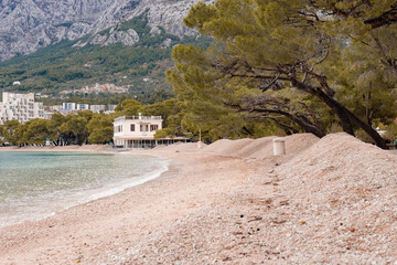 Makarska beach with heaps or piles of sand ready to be rolled on the beach, for a new season....