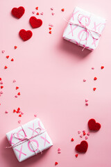 Gift boxes and red hearts decorations on pink table. Happy Valentines Day vertical background. Flat lay. Top view.