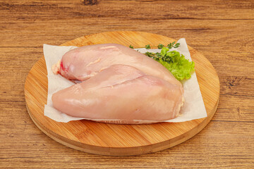 Raw chicken breast over board