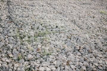 Granite stones behind a metal grate for strengthening the slope. Stones behind the wire. grey texture. construction.