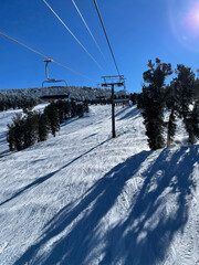 Fototapeta na wymiar View of chairlift and snow covered slopes at a ski resort on a bluebird winter day in Tahoe