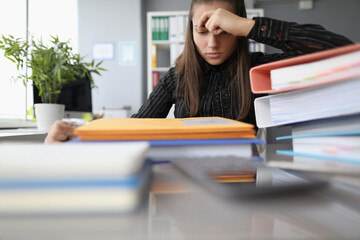 Tired overworked woman with hopeless look on docs pile