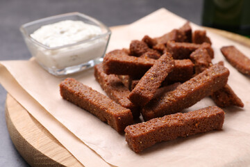Crispy rusks and dip sauce on wooden board, closeup