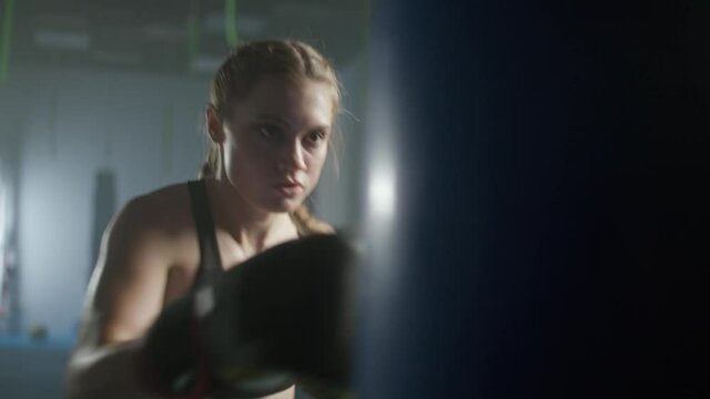 Woman power, female fighter trains his punches, beats a punching bag, training day in the boxing gym, the female strikes fast.