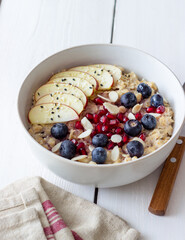 Oatmeal porridge with apple, pomegranate, blueberries and almonds. Healthy eating. Vegetarian food. Breakfast.