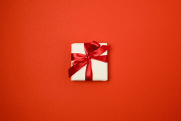 Gift box with red ribbon bow on red background. Top view