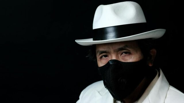 Close-up portrait of a masked man against black background
