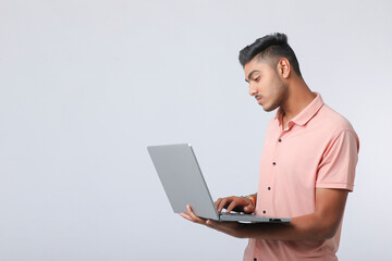 Young indian man using laptop on white background.