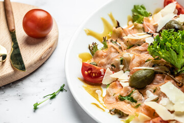 Appetizer salmon carpaccio with parmesan cheese, capers, parmesan and cherry tomatoes. Restaurant menu, dieting, cookbook recipe. top view