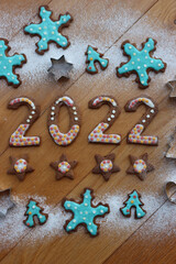 2022 made of cookies decorated with sugar glaze and colorful sprinkles on wooden table with various cookie cutters